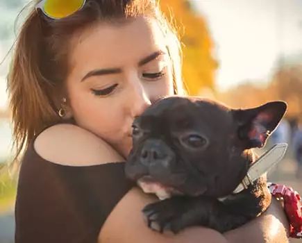 Woman hugging and kissing her puppy